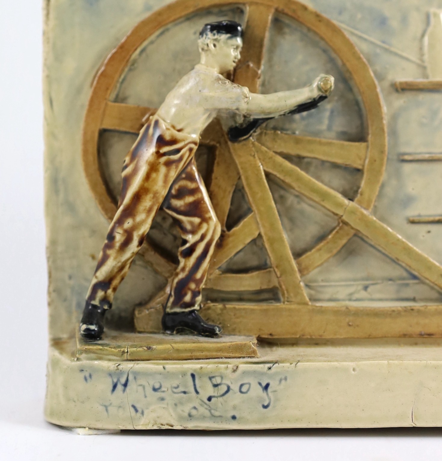 A rare Martin Brothers 'Wheel Boy, Bench Boy and Thrower' stoneware plaque, dated 1882, 41cm wide 17.5cm high